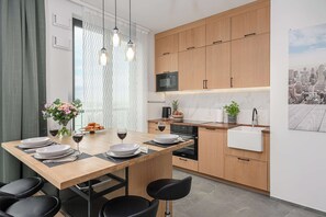 Une cuisine moderne avec des meubles en bois, un four à micro-ondes encastré et un coin repas avec une table mise pour deux personnes.