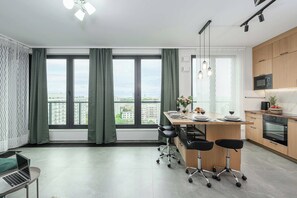 A modern kitchen with a dining area, large windows, and a view of the city. - Warsaw Flat With Balcony (Warsaw)
