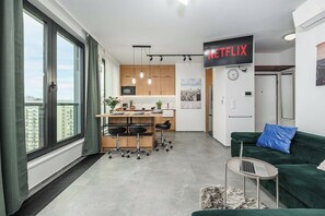 Eine moderne Wohnung mit Küche, Essbereich und Wohnraum. Ein großes Fenster bietet Blick auf die Stadt.