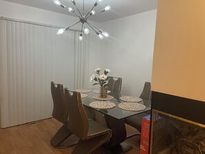 A dining area with a glass table, black chairs, a vase with flowers, and a ceiling light fixture. - Spacious 4BR; 2.5BR; en-suite;FL basement;appliances;central air& heat included! (Chicago)