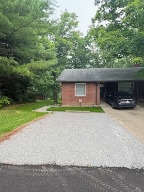 A residential property with a gravel driveway, a brick garage, and a car parked inside. - Cozy 1-bedroom apartment in wonderful Berlin with AC (Millersburg)