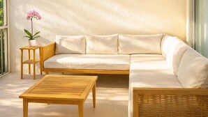 A modern living room with a sectional sofa, a wooden coffee table, a small side table with a potted plant, and a ceiling fan. - The Divine Tides Condo 5 Min Walk to Jupiter Beach (Jupiter)