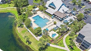 Eine Luftaufnahme eines Resorts mit einem großen zentralen Pool, mehreren kleineren Pools und einem Parkplatz.