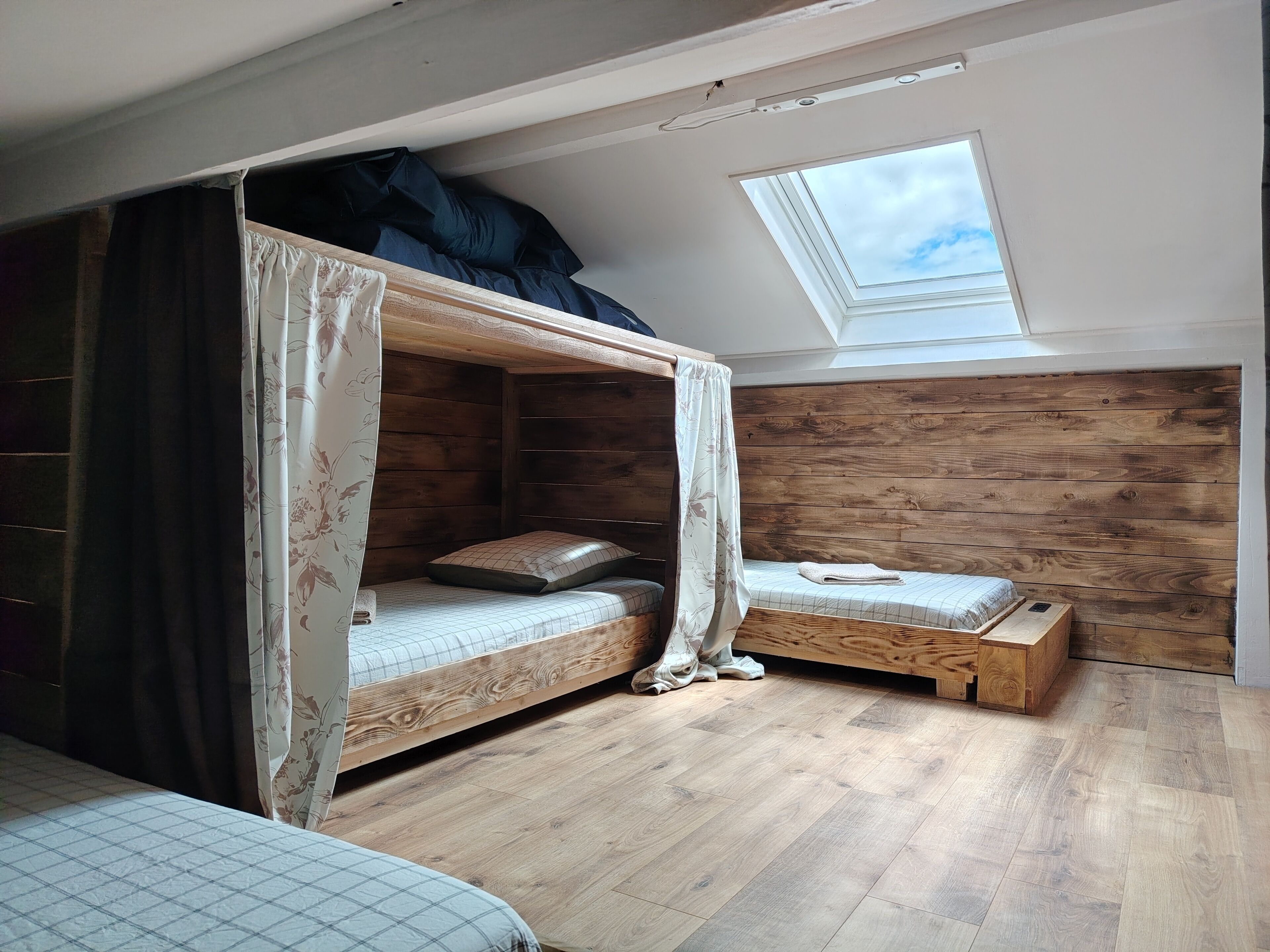 Ein Schlafzimmer mit Etagenbett, einem kleinen Nachttisch, einem Fenster und Holzboden.