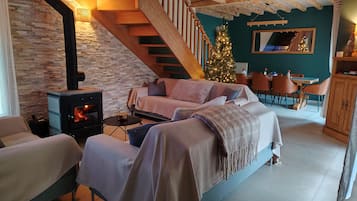 A cozy living room with a fireplace, a staircase, a Christmas tree, and a dining area.
