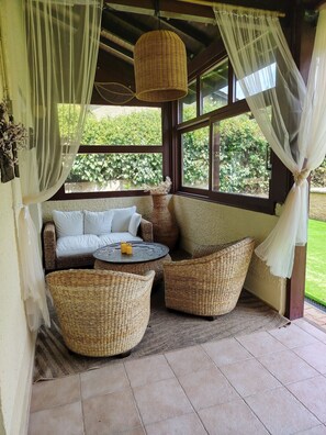 A cozy seating area with wicker furniture, a small round table, and sheer curtains. - Charming house with swimming pool,9 peoples,full equipement,family/pet friendly (Montmerle-sur-Saône)
