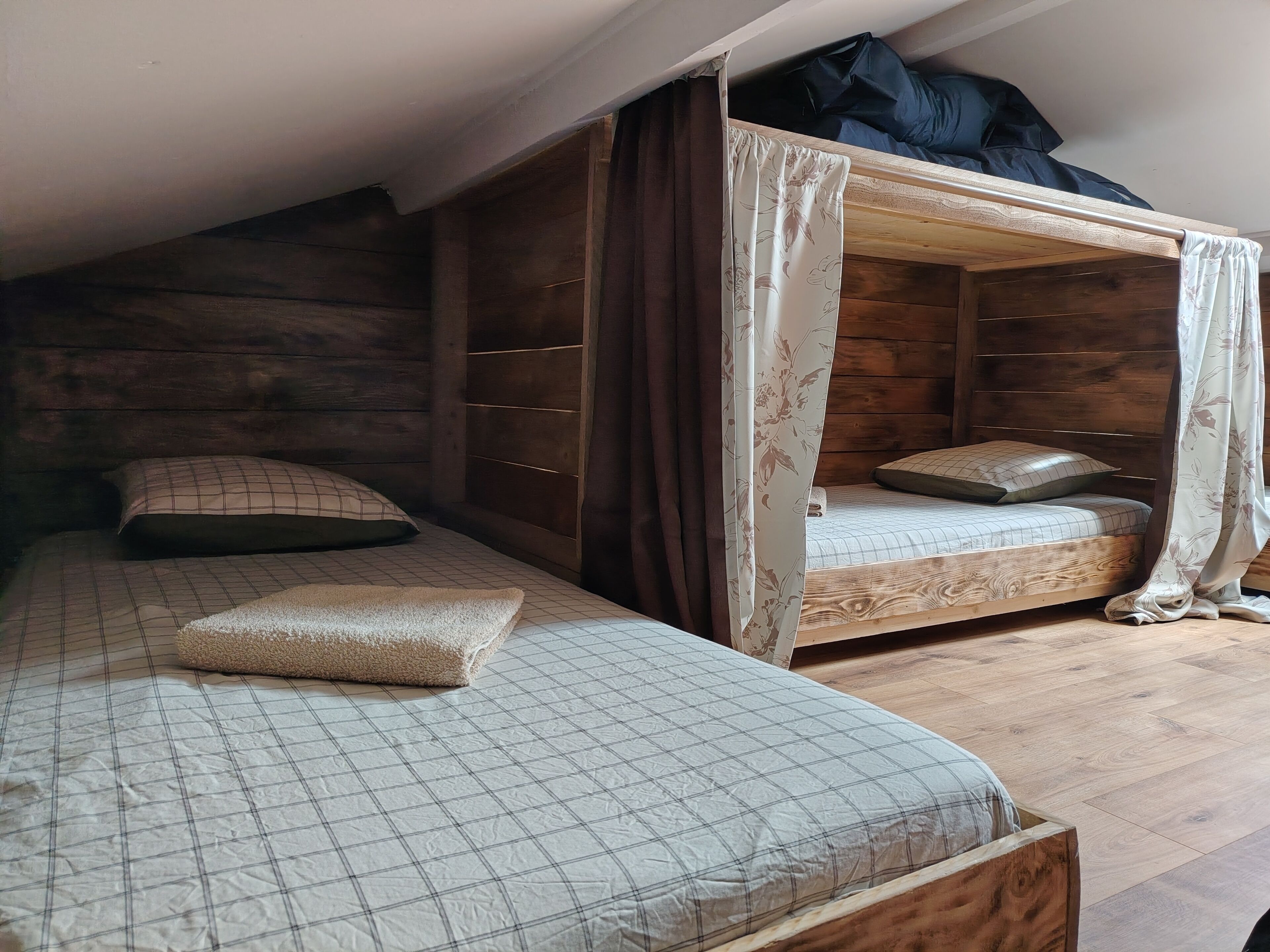 A room with two bunk beds, one with a canopy and wooden headboard, and the other with a plain headboard.