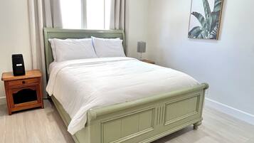 A bedroom with a bed, a nightstand, a ceiling fan, and a window with curtains.