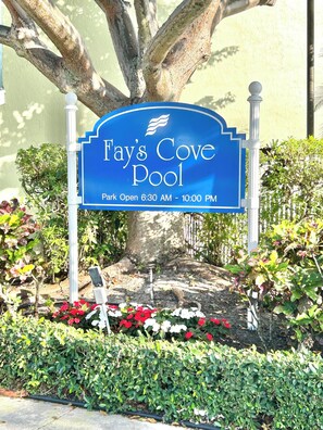 Schild für den Fay's Cove Pool mit Baum und Blumen im Hintergrund.