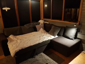 A room with a bed, a couch, and a window with blinds.