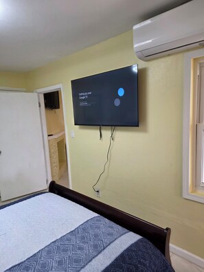 A bedroom with a bed, a television mounted on the wall, and a door leading to another room. - Newly Renovated Luxury Mountain Top Retreat 2BR 2BA Sleeps 4 (st thomas)