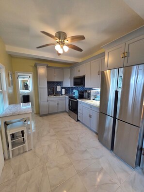A modern kitchen with white cabinets, stainless steel appliances, and a marble countertop. - Newly Renovated Luxury Mountain Top Retreat 2BR 2BA Sleeps 4 (st thomas)