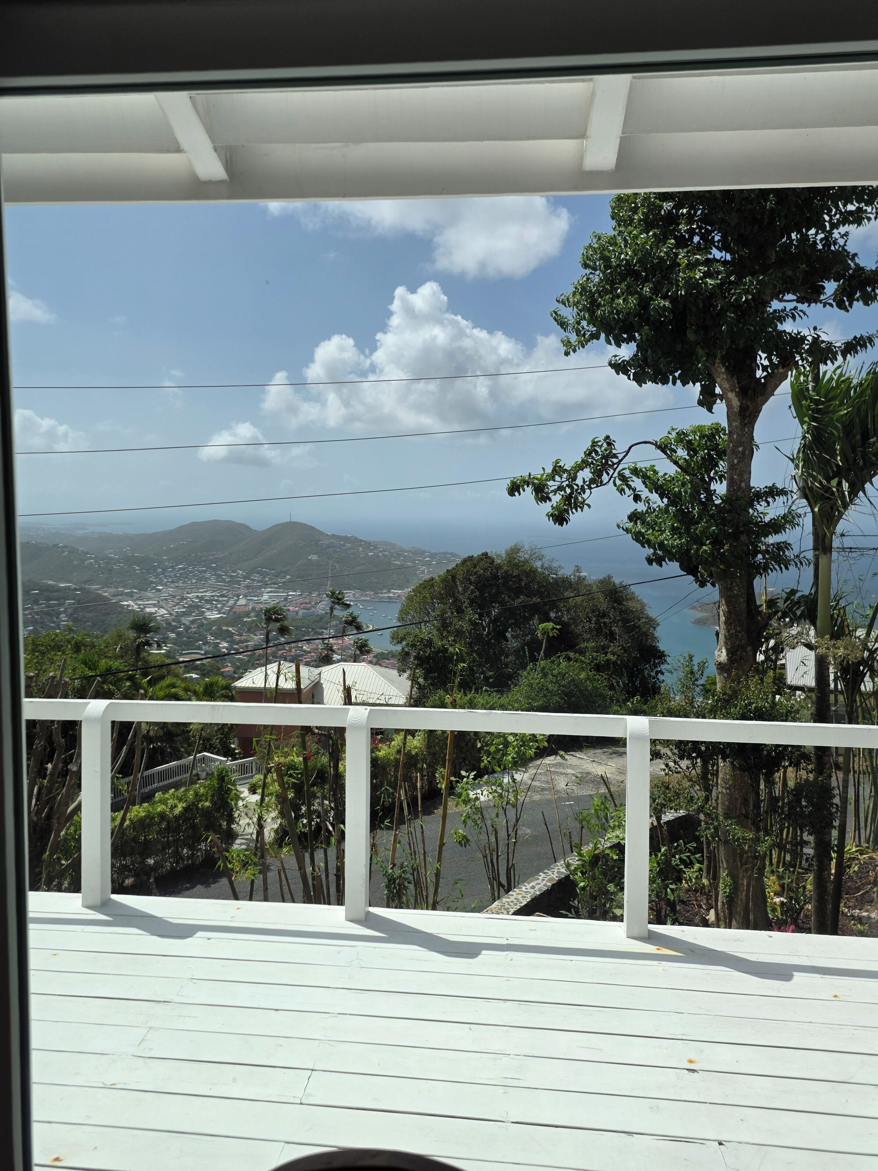 Uitzicht vanaf een balkon met een balustrade, uitkijkend over een kustlandschap met bergen en water.