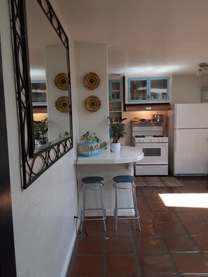 Cozinha com bancada branca, dois banquetes, fogão e armários.