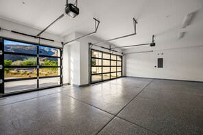 A spacious garage with large windows and a projector mounted on the ceiling. - Brand-New, Spacious Desert Oasis - Pool, Spa & Mountain Views (La Quinta)