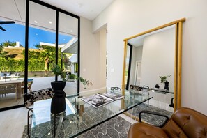 Un intérieur moderne avec une table à manger en verre, un canapé en cuir et un grand miroir.