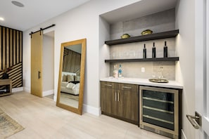 Une cuisine moderne dotée d’un meuble à vin intégré, d’un grand miroir et d’un réfrigérateur à porte vitrée.