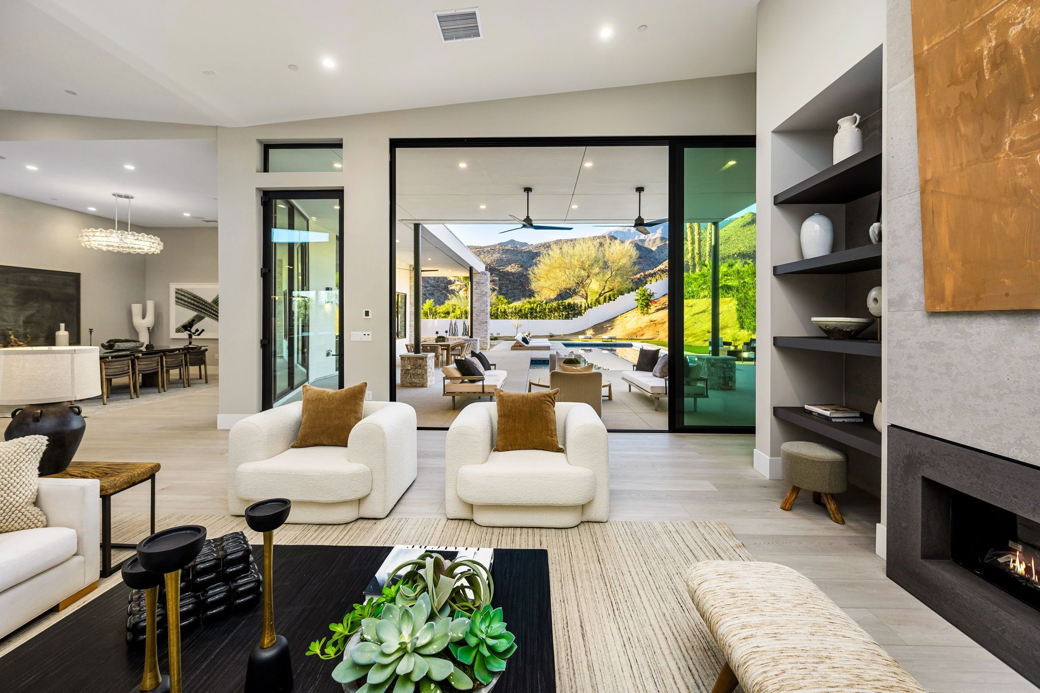A modern living room with a fireplace, seating area, and a view of a mountainous landscape.