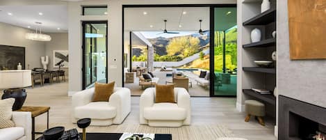 Una sala de estar moderna con chimenea, zona de estar y vistas a un paisaje montañoso.
