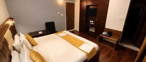 A hotel room with a large bed, a desk, a wardrobe, and a ceiling fan.