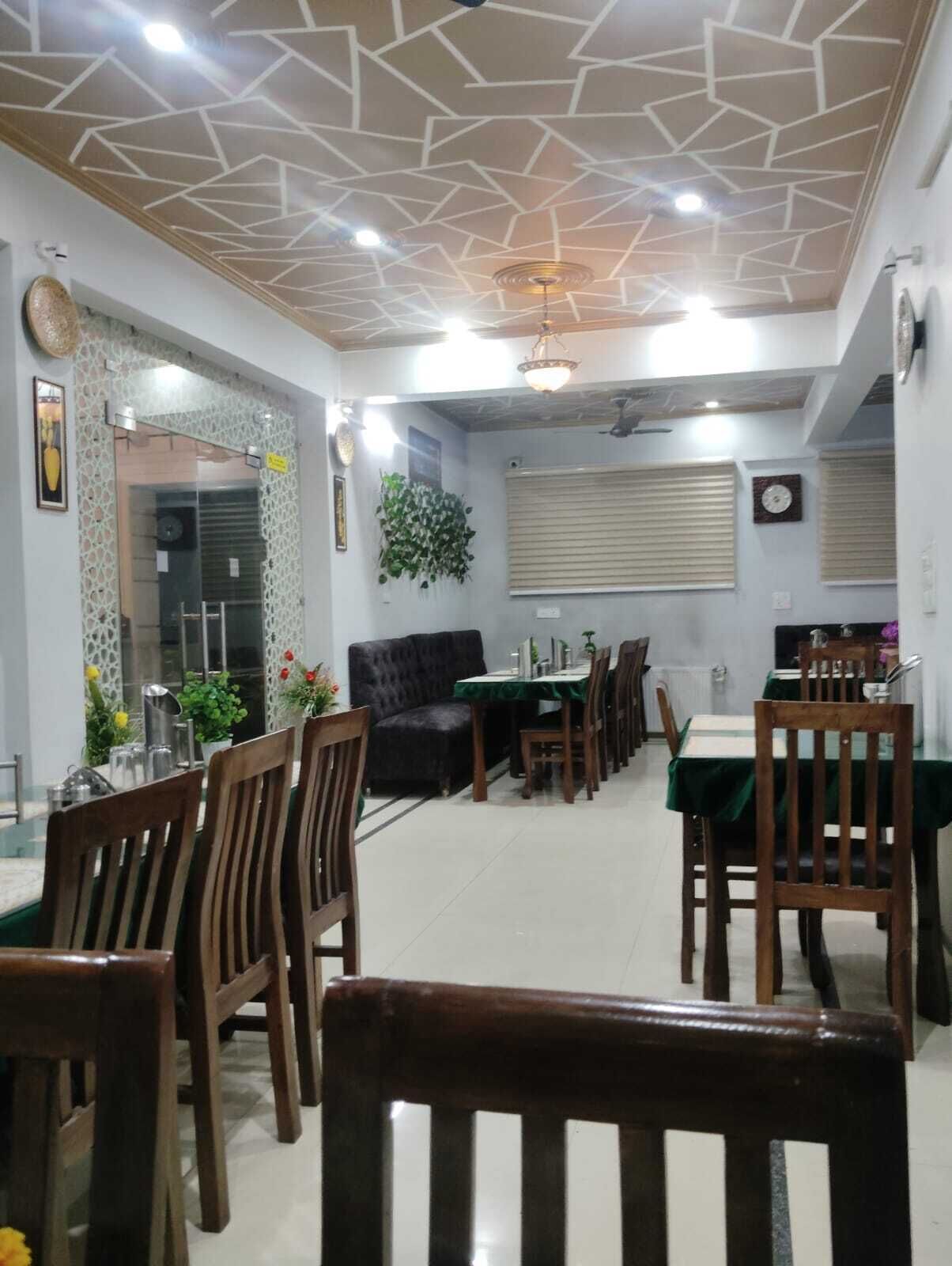 A dining area with a geometric ceiling design, a sofa, and a dining table set for four.