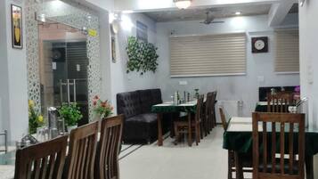 A dining area with a geometric ceiling design, a sofa, and a dining table set for four.
