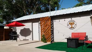 Un espace extérieur aménagé avec un barbecue, un parasol rouge et des sièges.