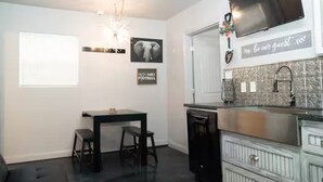 Une cuisine avec un coin repas, un téléviseur fixé au-dessus du comptoir et un panneau sur le mur.