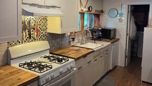 A modern kitchen with white cabinets, a gas stove, and a wooden countertop. - Cozy 1-bedroom apartment in charming Sky Valley, GA. 11 miles from Highlands, NC (Dillard)