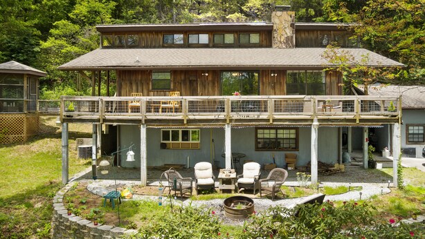 A two-story wooden house with a balcony, outdoor seating, and a fire pit. - Cozy 1-bedroom apartment in charming Sky Valley, GA. 11 miles from Highlands, NC (Dillard)