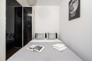 A modern bedroom with a bed, pillows, a magazine, and a towel. - Central Warsaw Home With Garage (Warsaw)