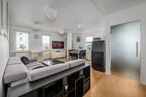 A modern living room with a sofa, a dining table, a TV, and a refrigerator. - Central Warsaw Home With Garage (Warsaw)