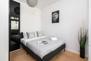 A modern bedroom with a bed, a bedside table, a hanging light fixture, a wall-mounted picture, and a potted plant. - Central Warsaw Home With Garage (Warsaw)