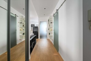 A hallway with a kitchen area, wooden flooring, and built-in shelving units. - Central Warsaw Home With Garage (Warsaw)