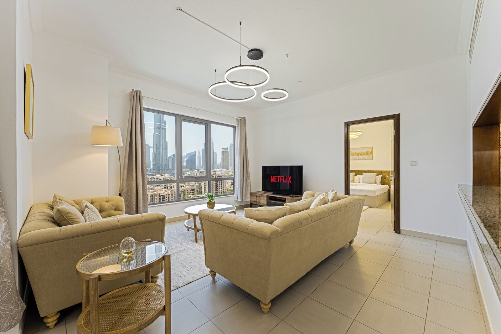 A modern living room with a sofa set, a TV, and a dining area with a table and chairs.