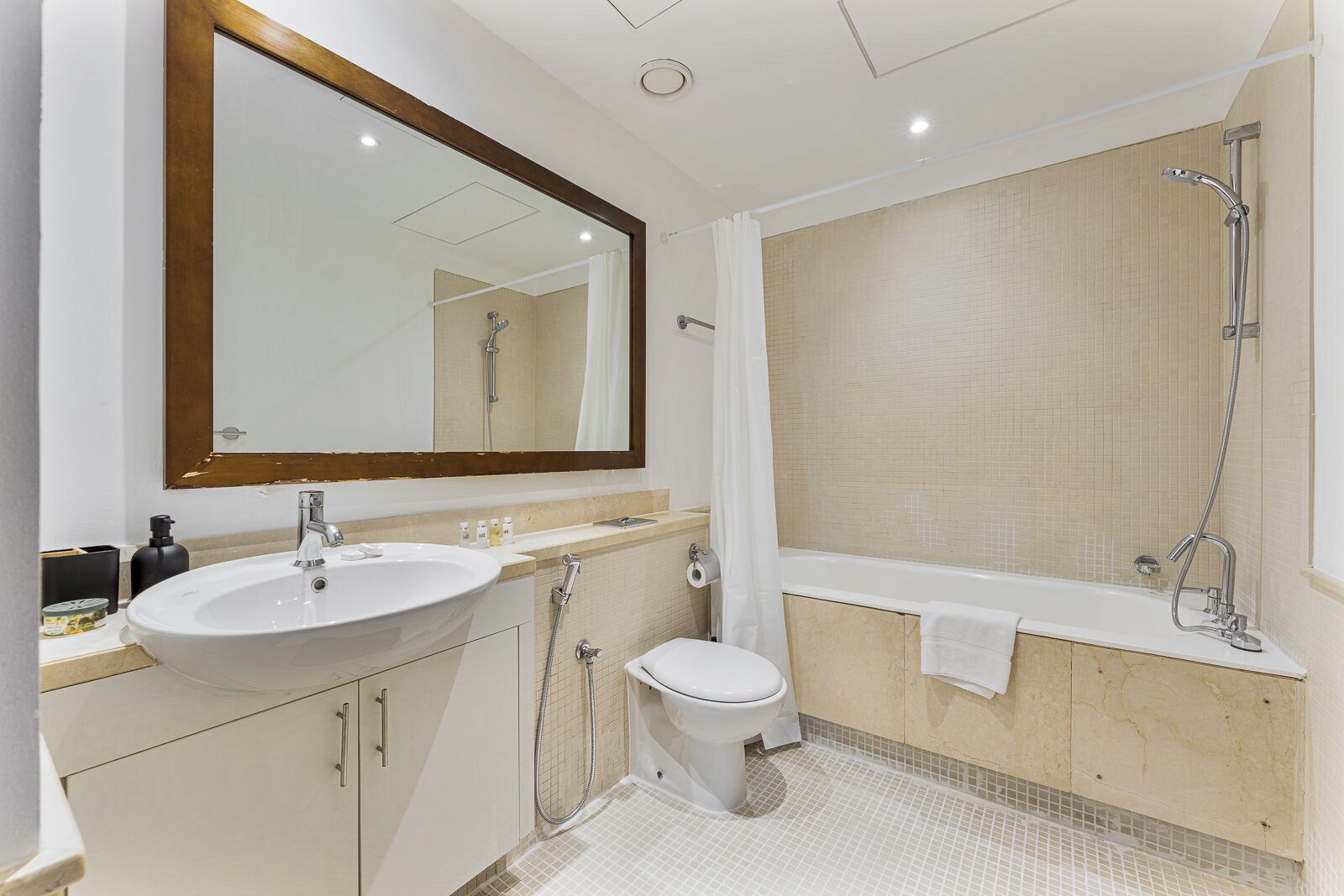 Ein modernes Badezimmer mit großem Spiegel, Waschbecken, Toilette und Badewanne.