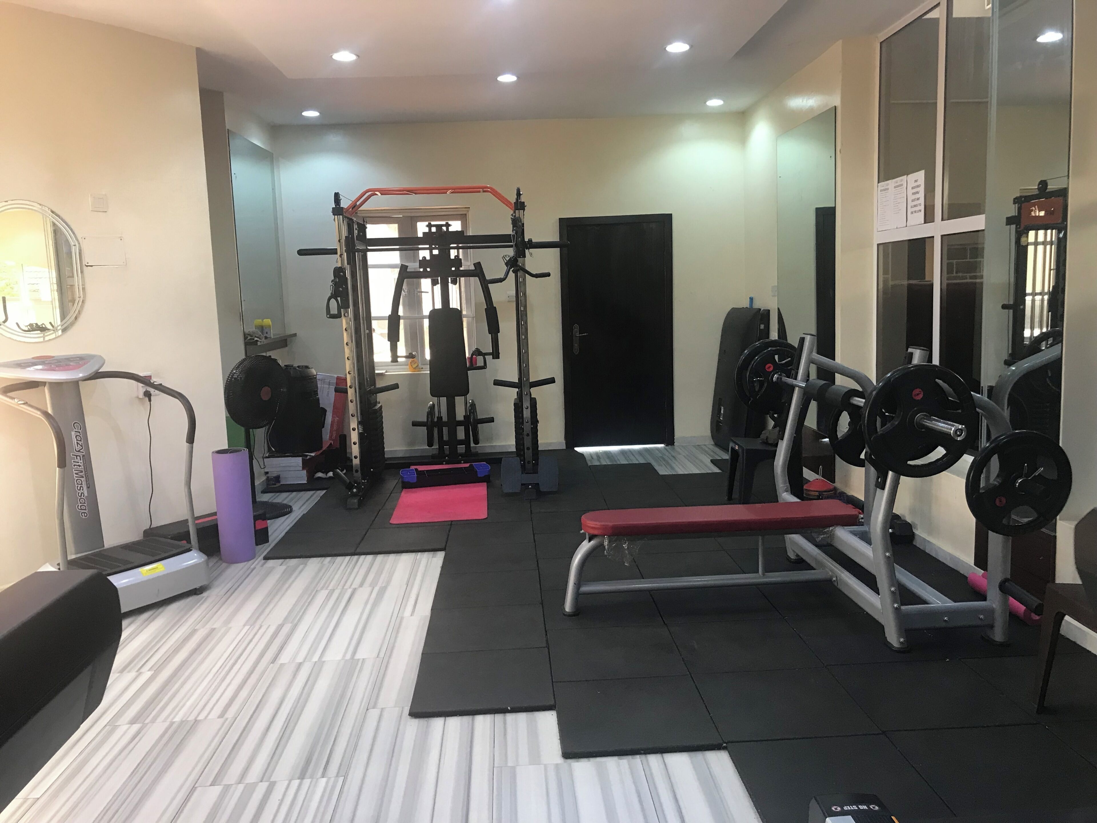 Ein Fitnessraum mit Trainingsgeräten, Laufband und Spiegel.