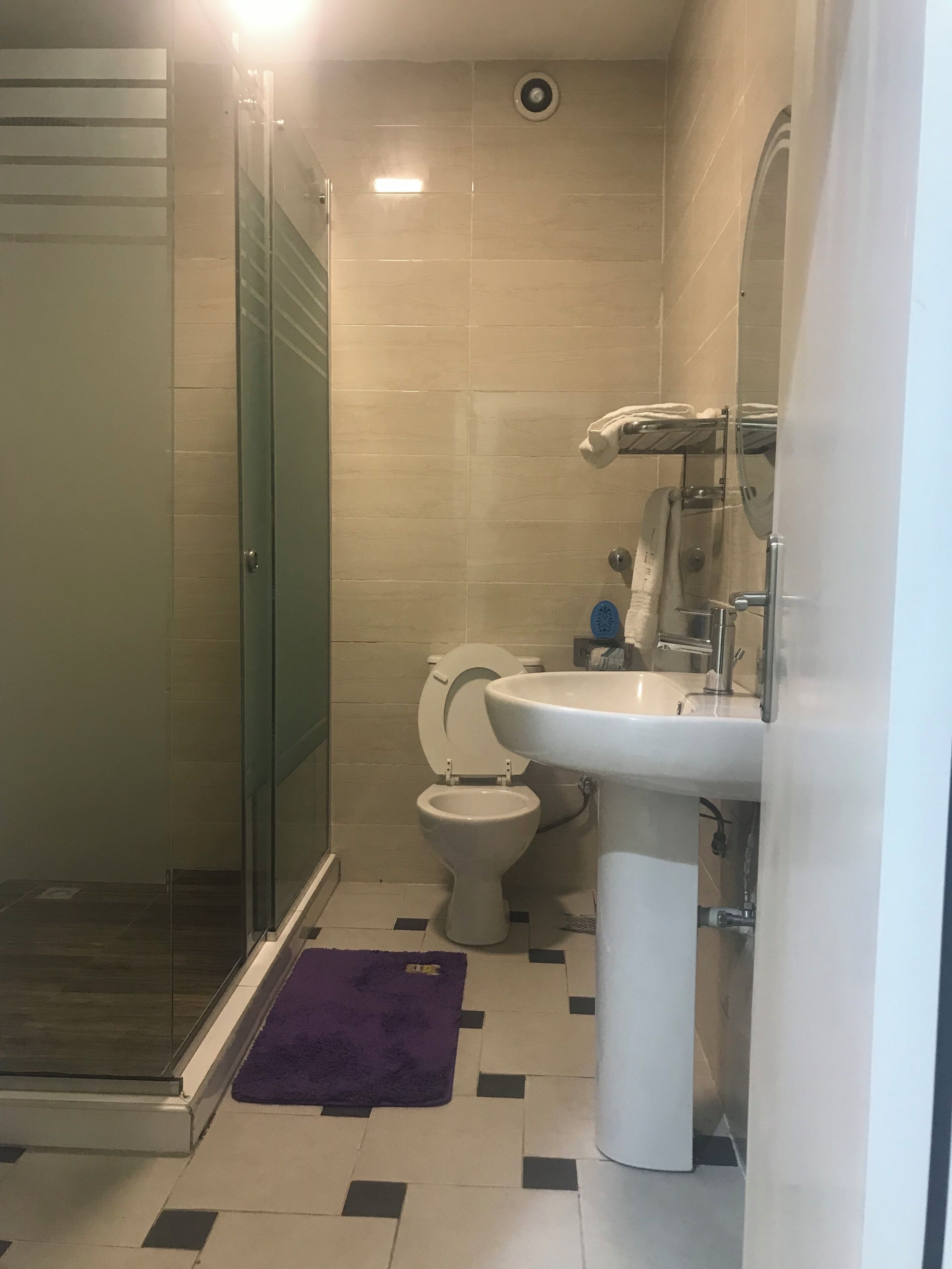 Un baño con cabina de ducha de vidrio, inodoro y lavamanos.