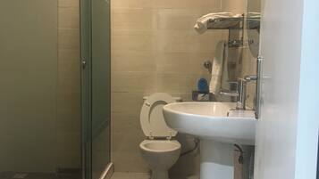 Un baño con cabina de ducha de vidrio, inodoro y lavamanos.