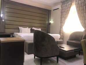 Una habitación de hotel con cama, sofá, mesa de centro y escritorio.