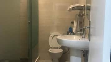 Un baño con cabina de ducha de vidrio, inodoro y lavamanos.