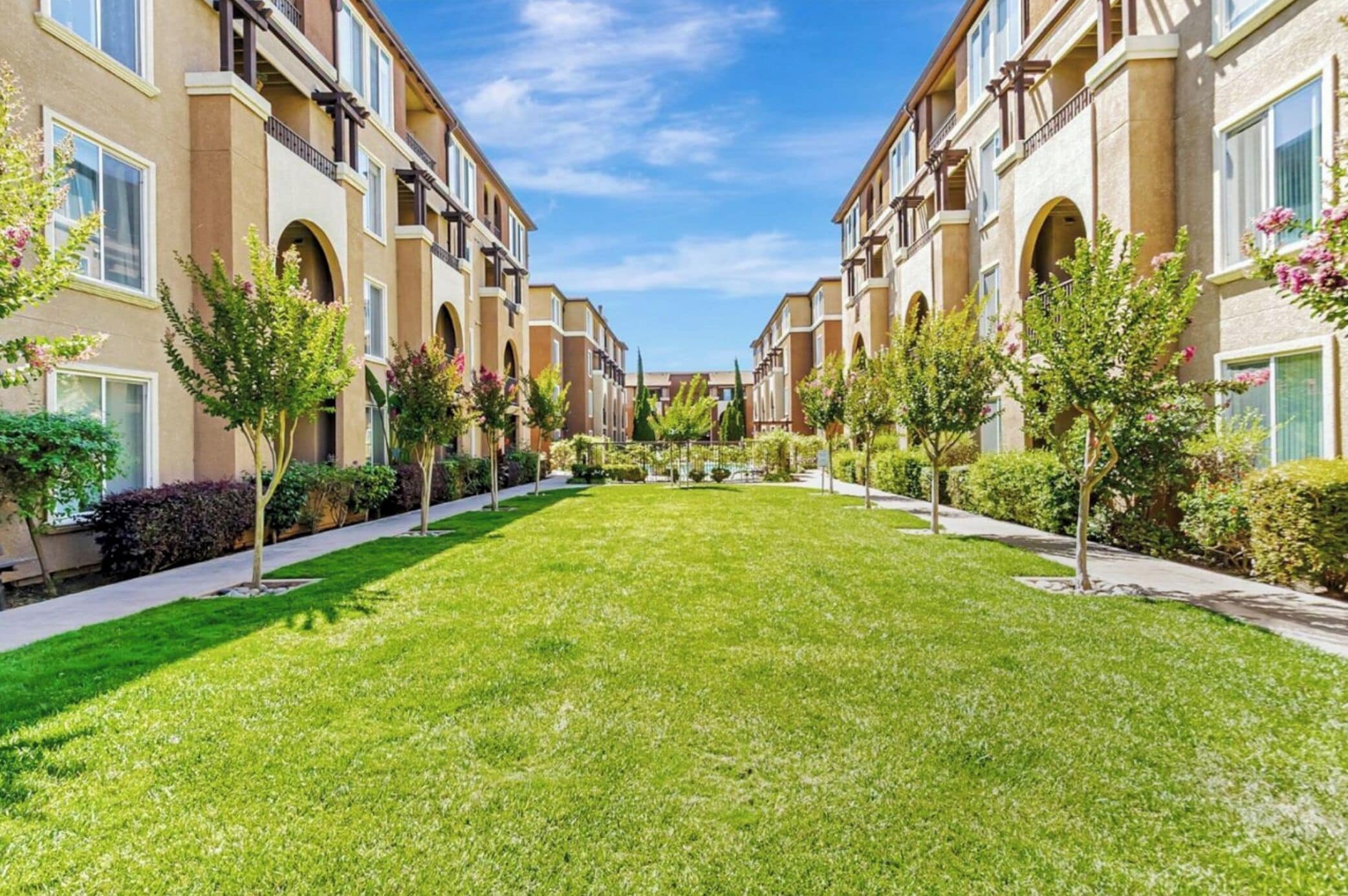 A courtyard with a central lawn, surrounded by multi-story buildings with balconies and arched windows.