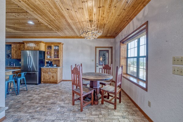 A kitchen with wooden cabinets, a stainless steel refrigerator, and a dining table with chairs.