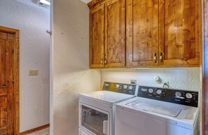 A laundry room with wooden cabinets, a washing machine, and a dryer.