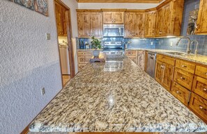 A kitchen with granite countertops, wooden cabinets, a stainless steel oven, and a microwave.