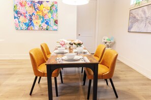 A dining area with a wooden table set for six, surrounded by orange chairs. - Luxy-Master BRD Down - 7Beds - Near CLT Uptown (Charlotte)