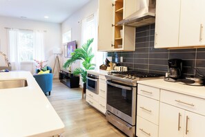 A modern kitchen with stainless steel appliances, white cabinetry, and a large window providing natural light. - Luxy-Master BRD Down - 7Beds - Near CLT Uptown (Charlotte)