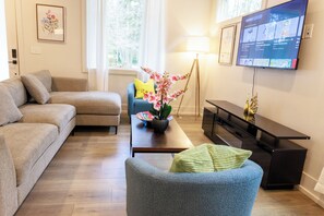 Un salon comprenant un canapé, un fauteuil, une table basse et un téléviseur fixé au mur.