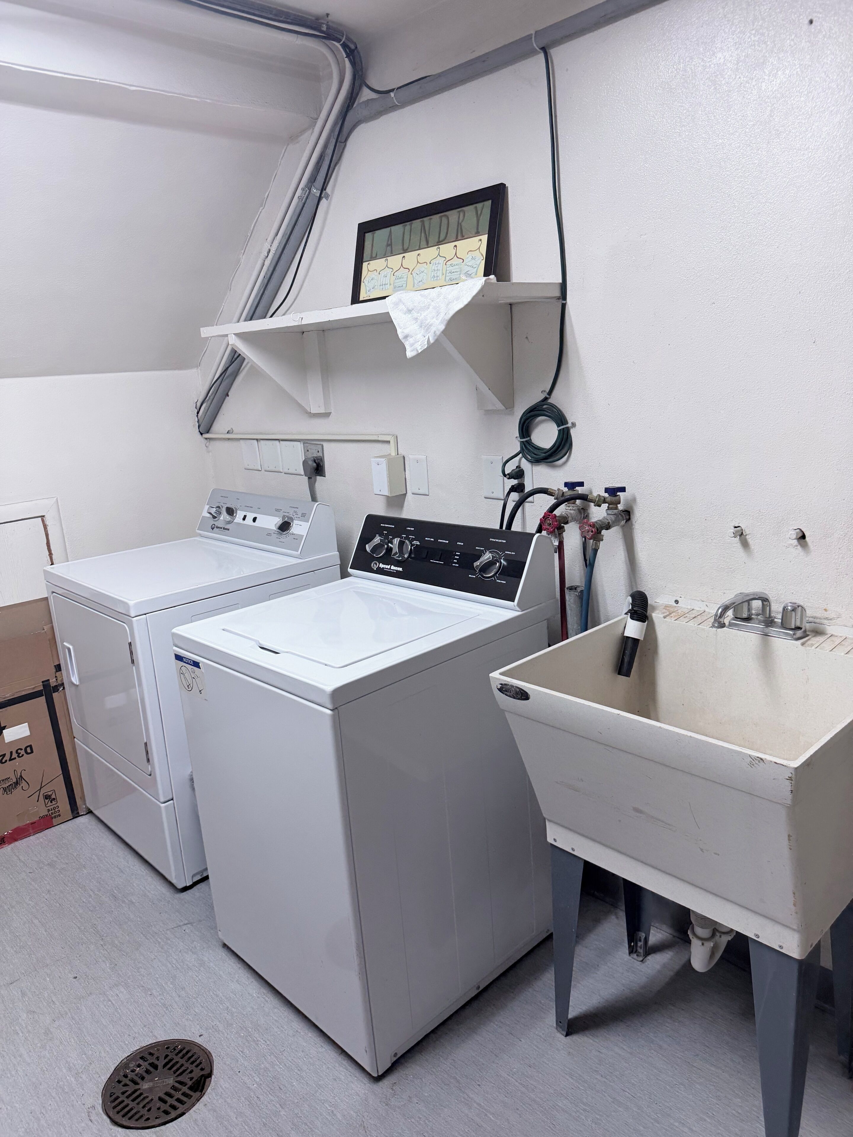 A laundry area with a washing machine, a drying machine, a sink, and a shelf with a towel.