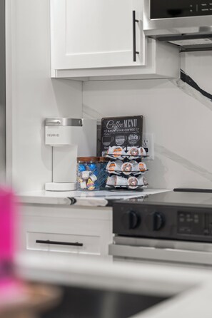 A kitchen with a Keurig coffee maker, a coffee menu sign, and a coffee dispenser.